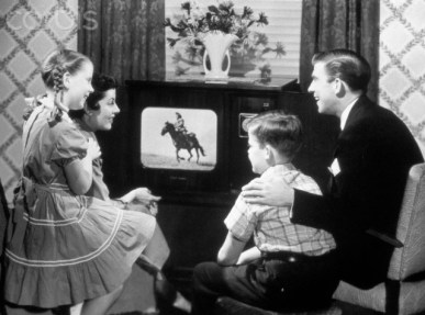 1950s family of four watching black and white television program of a cowboy riding a horse
