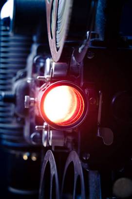 Detail of an old-fashioned 16mm film movie projector with the light on